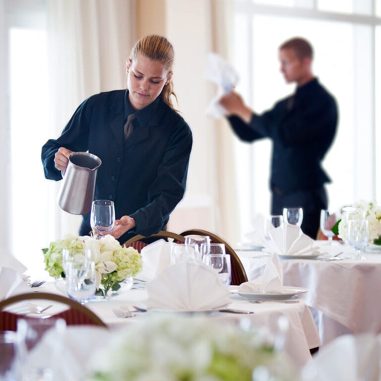 Temporary catering workers setting tables before an event