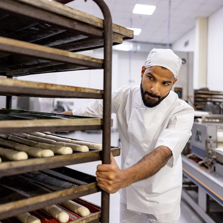 A temp bakery worker moves a cart of bread