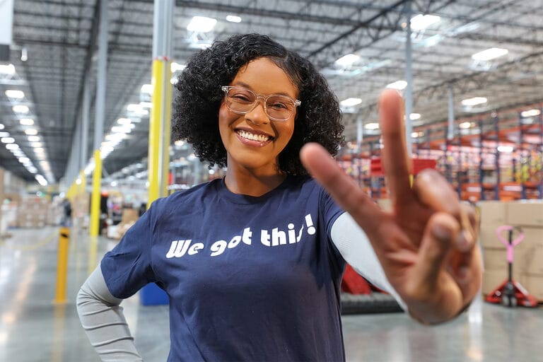 A temporary warehouse worker wearing a t-shirt reading "We got this!"